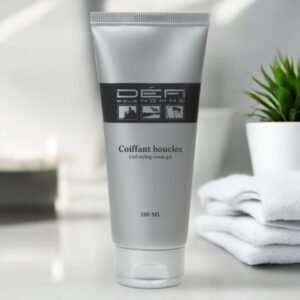 Un tube argenté étiqueté « Défi pour Homme Coiffant boucles Curl styling cream gel, 100 ML » est posé sur le comptoir d'une salle de bain à côté de serviettes blanches pliées et d'une petite plante verte. L'arrière-plan est doucement éclairé par la lumière naturelle.