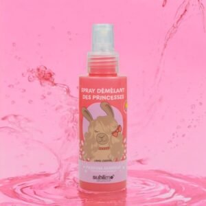 Un flacon pulvérisateur rose étiqueté « Spray Démêlant des Princesses » avec un lapin illustré portant un noeud. Le flacon porte la mention « Parfum Mangue » indiquant un parfum de mangue. Il est posé sur un fond rose avec des éclaboussures d'eau.