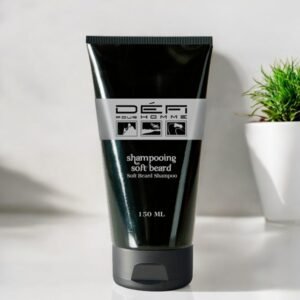 Un tube noir de shampoing pour barbe étiqueté « Défi Pour Homme » avec des accents argentés, contenant 150 millilitres. Le tube est placé sur une surface blanche à côté d'une petite plante verte dans un pot blanc.