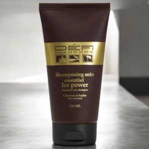 Un tube brun foncé de 150 ml de shampoing pour cheveux et barbe Défi Pour Homme Ice Power Essential Care est placé sur une surface réfléchissante. L'étiquette comporte du texte en français et en anglais, et le design aux accents dorés souligne son aspect haut de gamme.