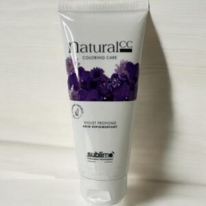 Un tube blanc de produit capillaire Sublimo Natural CC Coloring Care est présenté sur un fond clair. L'étiquette comporte des fleurs violettes et le texte « Violet Profond - Soin Répigmentant » accompagné d'un logo indiquant qu'il est testé dermatologiquement.