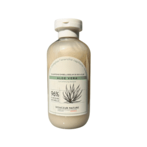 Un flacon transparent de 250 ml de « Shampoing Douceur Sublimo Aloé Vera Douceur Nature », muni d’un bouchon blanc et d’une étiquette portant la mention « 96 % d’origine naturelle » ainsi qu’une illustration d’un aloès, mettant en avant sa formule douce et hydratante pour des cheveux soyeux.