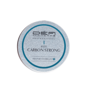 Une boîte ronde en argent portant l'inscription « Pâte Carbon strong - Défi pour Homme - 75 ml », rehaussée d'une bordure et d'un texte bleus, offre une tenue forte et un fini brillant — idéale pour tous ceux qui recherchent une coiffure durable et un contrôle parfait grâce à cette pâte coiffante professionnelle pour homme de la marque Défi.