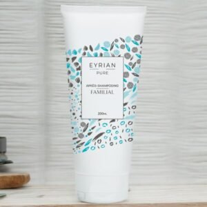 Un tube blanc d'après-shampoing Eyran Pure Familial est posé sur une surface en bois sur un fond clair. Le tube présente un motif avec des feuilles et des baies bleues, noires et grises autour de l'étiquette. Le texte indique que le produit est un après-shampoing de 200 ml.