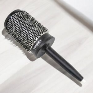 La Brosse Ronde Termix – Diamètre 43, une grande brosse à cheveux ronde avec un manche noir et un corps cylindrique doté de poils en métal, repose sur une surface de couleur claire, avec le nom de la marque « Termix » imprimé sur la base métallique du corps.