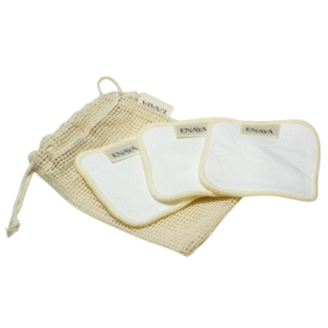 Trois Set de 3 Cotons Démaquillants Naturels-Enaya blancs avec des bords crème et des étiquettes "ENAYA" sont présentés sur un sac à cordon en maille beige, avec un coussin partiellement à l'intérieur du sac.