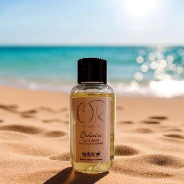 Un petit flacon d'Huile Elixir-Or Infinite Solaire - 50 ml repose sur une plage de sable avec un océan turquoise et un ciel bleu clair en arrière-plan. La lumière du soleil scintille sur le flacon, mettant en valeur son étiquette sur laquelle est écrit « Solaire ».