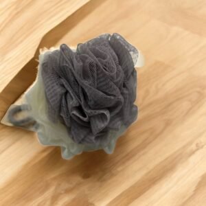 Une Fleur de douche Beige Amande (Copie) texturée beige, enveloppée dans du papier brun, repose élégamment sur une surface en bois.