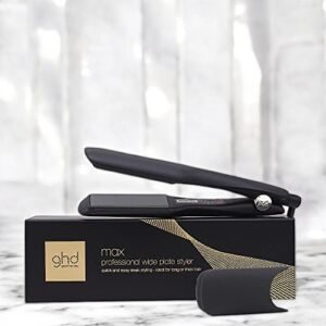 Un lisseur GHD Cheveux-Styler Max est posé sur sa boîte noire. L'arrière-plan présente une surface en marbre légèrement floue, avec un couvercle de protection thermique placé devant la boîte.