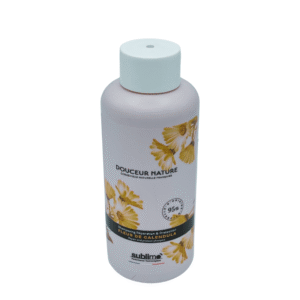 Un flacon rose au bouchon blanc, étiqueté « Douceur Nature », orné de fleurs de calendula jaunes. Le shampoing Douceur fleur de calendula-Sublimo (250 ml) contient 95 % d'ingrédients d'origine naturelle de la marque Sublimo.