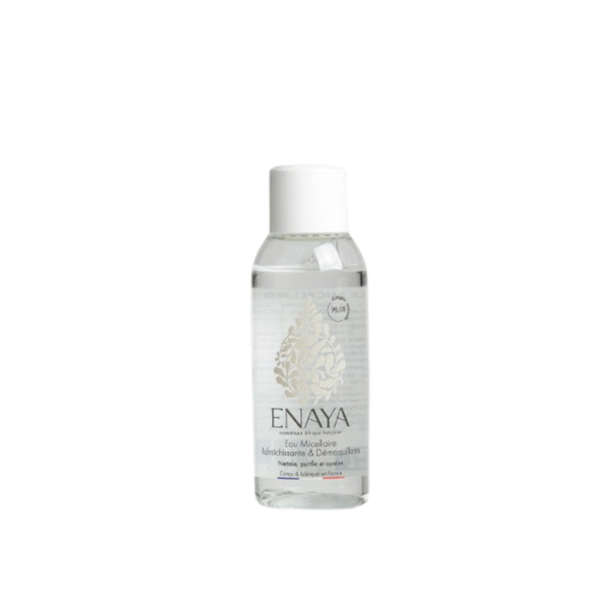 Le flacon en plastique transparent de 45 ml de l'Eau micellaire rafraichissante et démaquillante ENAYA est doté d'un bouchon à vis blanc, d'une étiquette florale dorée et d'un texte gris clair. Ce liquide transparent démaquille en douceur et rafraîchit la peau.