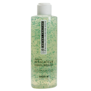 Une bouteille en plastique transparent de 200 ml de Shampooing Régulateur Équilibrant -Instant Traitant- avec gel vert et perles bleues, étiquetée « Soin Régulateur Cuir Chevelu Équilibrant », comporte un capuchon rabattable blanc pour équilibrer et réguler les cheveux.