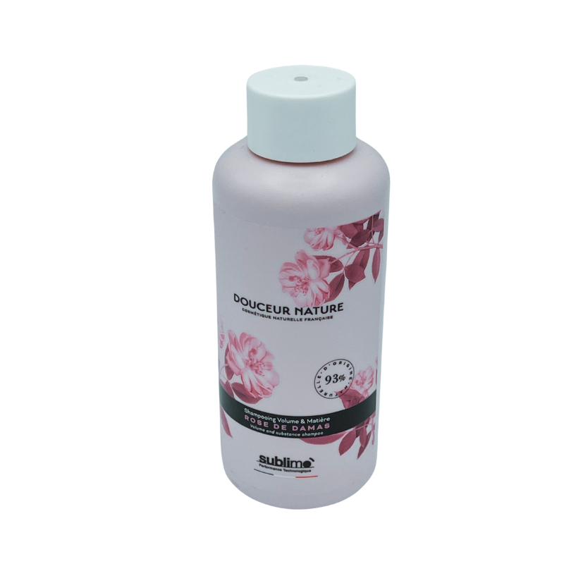 Un flacon rose de 250 ml de Shampoing Douceur Rose de Damas-Sublimo, orné d'illustrations de roses et étiqueté « Douceur Nature », offre une touche sublime et élégante pour une expérience de soin capillaire luxueuse.