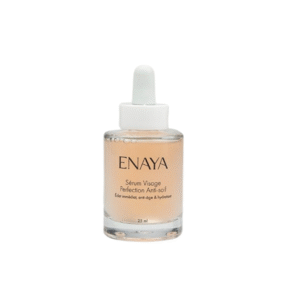 Un flacon compte-gouttes en verre transparent étiqueté « Sérum visage perfection anti-soif -Enaya-25 ml » avec un sérum pêche clair à l'intérieur se tient debout sur un fond blanc.