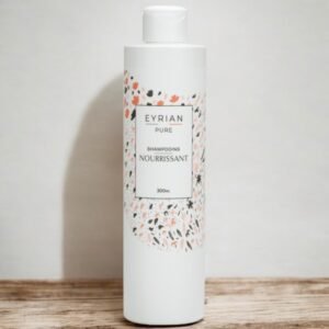 Un flacon cylindrique blanc de shampoing Eyrian Pure Nourrissant, 300 ml, est posé sur une surface en bois sur un fond clair. Le flacon présente un motif floral en rouge, noir et vert autour de la zone d'étiquette.