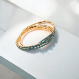 Deux élégants bracelets élastiques en métal et strass bleu ciel, idéaux pour une superposition chic de bracelets, sont posés sur une surface blanche. La lumière du soleil crée des ombres douces, mettant en valeur le scintillement des bijoux.