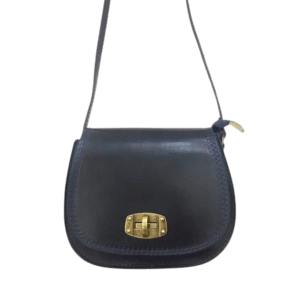 Le Sac à bandoulière en cuir rigide est un petit sac en cuir bleu foncé, doté d'une longue lanière et d'un fermoir à boucle tournante en métal doré sur le rabat avant, sur fond blanc.