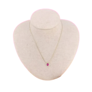 Le Collier court et son pendentif cristal forme goutte / Fushia, un collier délicat avec un pendentif en cristal en forme de goutte fuchsia, est présenté sur un buste à bijoux beige sur fond blanc.