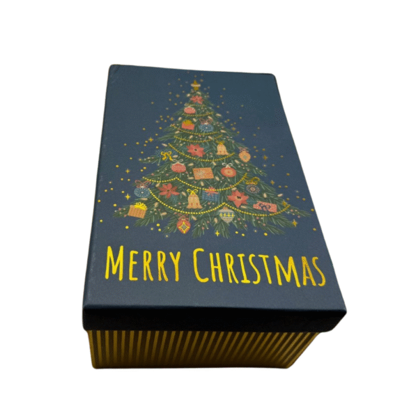 La Boîte Cadeau -Rectangulaire -Noël -Grand Sapin Noël est ornée d'un sapin de Noël décoré et du mot "Merry Christmas" en jaune sur son couvercle bleu foncé aux côtés rayés d'or - idéal pour les cadeaux festifs.