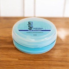 Un récipient rond contenant un produit de soin crème Sculptante-Eyrian de couleur bleue, posé sur une surface en bois. Le couvercle présente des détails textuels en noir et bleu.