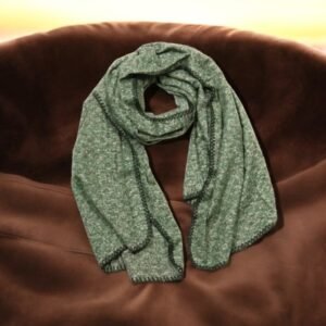 Une écharpe verte avec un motif texturé est soigneusement disposée en forme circulaire sur une surface lisse et marron.