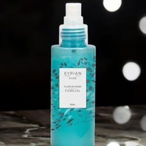 Un flacon de Fluide Bi-Phase - Eyrian, 100 ml. Le récipient translucide met en valeur un liquide bleu vif orné de motifs de feuilles noires sophistiquées. Posé sur une surface en marbre, il scintille contre la douce lueur des lumières floues en arrière-plan.