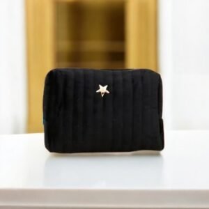 Une petite pochette matelassée noire repose sur une surface blanche. Elle présente un emblème en forme d'étoile argentée brillante au centre et se détache sur un arrière-plan flou.