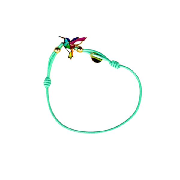 Un fin bracelet à cordon réglable turquoise est orné d'une breloque colibri/Amande en acier inoxydable laqué argent et de petites perles dorées, présentées sur un fond blanc.