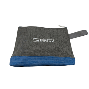 Trousse de toilette grise Défi pour Homme avec fond bleu, fermeture zippée et bride latérale en tissu. « Den Bou Homme » est imprimé en blanc sur le devant.