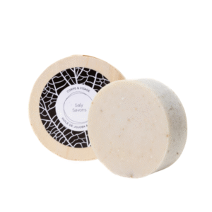 Deux pains ronds beiges : l'un debout avec l'étiquette « Corps & Visage » en noir et blanc, l'autre à plat. Voici le Savon Jojoba et Rassal-120 g-Saly Cosmétiques, un savon nettoyant doux au jojoba et au rassal.