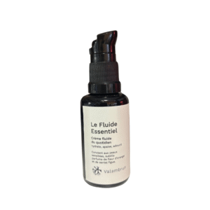 Un petit flacon pompe noir étiqueté « Le Fluide Essentiel 30 ml- Peau sensible » de Saly Cosmétiques, décrit comme un fluide hydratant apaisant pour les peaux sensibles, se dresse sur un fond blanc.