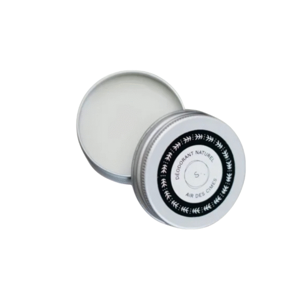 Une boîte métallique ronde et ouverte de Déodorant Air des Cimes 30 g de Saly Cosmétiques est posée sur un fond blanc. Son couvercle, mis de côté, arbore une étiquette noire et blanche avec du texte et un simple motif de feuillage.