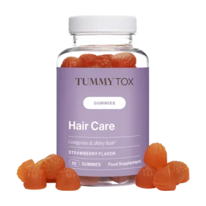 Un flacon transparent étiqueté « Gummies Hair Care - Tummy Tox » et doté d'une étiquette violette contient des gummies orange en forme de fraise. Plusieurs de ces gummies sont également dispersés au fond du flacon.