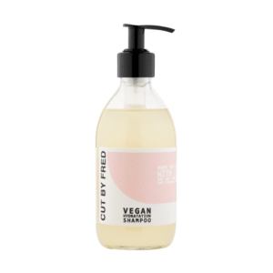 Un flacon pompe transparent de Shampooing Hydratant -Vegan-290ml de Cut by Fred, doté d'une étiquette rose clair et blanche avec texte noir et distributeur, rempli de liquide jaune pâle - votre soin capillaire hydratant végétalien essentiel.