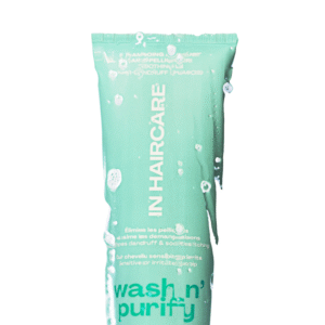 Un tube vert de "Shampoing apaisant : Wash n' Purify -250ml-In Hair Care" avec des gouttes d'eau et du texte en français et en anglais sur l'élimination des pellicules et le soulagement des cuirs chevelus sensibles ou irrités.