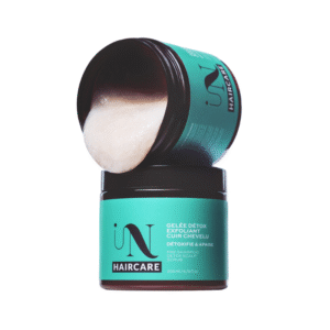 Un pot turquoise et marron de Gelée Détox Gommage Cuir Chevelu (200 ml, en soin capillaire) est ouvert, son couvercle biseauté révélant l'exfoliant onctueux qu'il contient. L'étiquette indique le nom et les informations du produit.