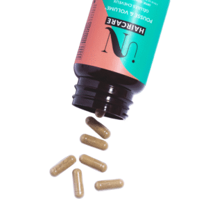 Un flacon de Gélules - Cure pousse de cheveux - In Hair Care renversé sur le côté avec sept capsules beiges débordant sur une surface blanche.
