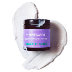 Un pot de Masque Repair n' Care-250ml-In Hair Care avec une étiquette violette et verte repose sur un tourbillon de masque blanc crémeux sur un fond blanc.