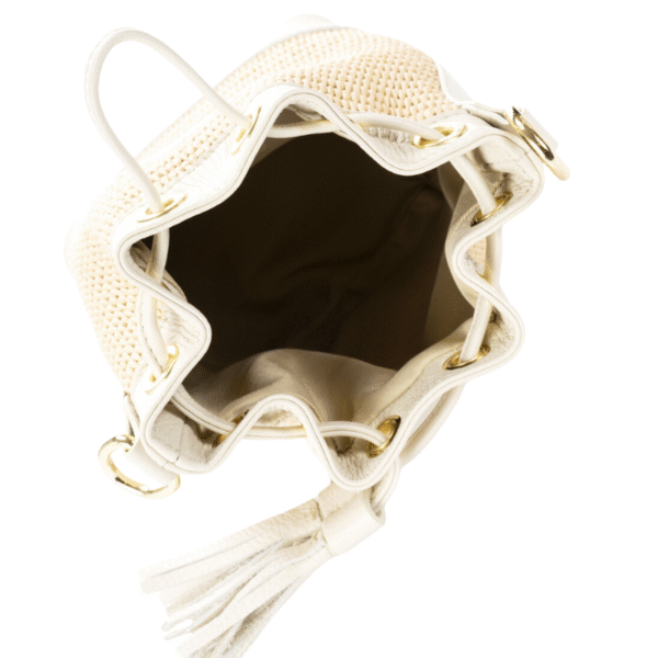 Le Sac Raphia et cuir véritable - Bandoulière réglable-Vanille est un sac seau tissé beige et blanc avec des ferrures dorées, un cordon de serrage et un pompon, présenté ouvert par le haut sur un fond blanc.