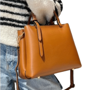 Une personne en pull rayé et jean porte le Sac à main en cuir grainé compartimenté-Noir (Copie), doté de poignées courtes et d'une longue bandoulière.