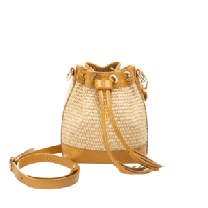 Le Sac Raphia et cuir véritable - Bandoulière réglable-Camel est un petit sac seau en paille tressée avec des bordures en cuir irisé, des œillets dorés, un cordon de serrage et une sangle réglable, le tout sur fond blanc.