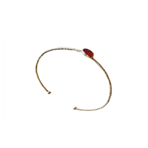 Un bracelet en acier inoxydable de couleur or, "Bracelet jonc en acier inoxydable ou et strass rouges", présente au centre un seul strass rouge, évoquant l'élégance raffinée sur fond blanc.