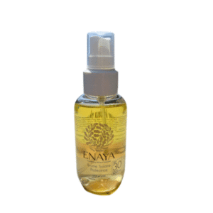 Un flacon vaporisateur transparent de « Brume solaire protectrice – Enaya – 90 ml », muni d'un bouchon pompe blanc et contenant un liquide doré, présenté sur un fond blanc.